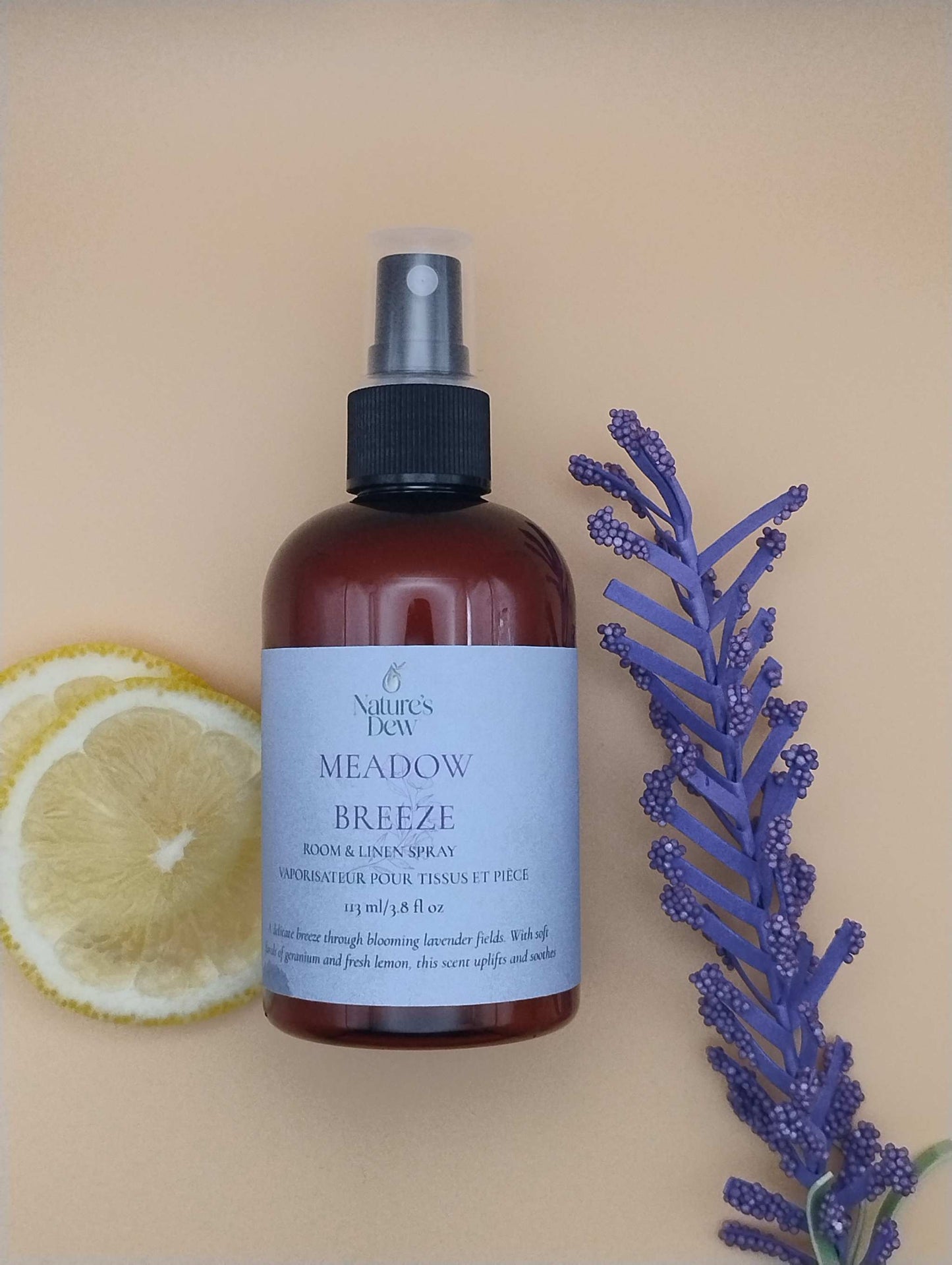 Meadow Breeze Room & Linen Spray bottle with lavender sprig and lemon slices, symbolizing calming floral-citrus scent.