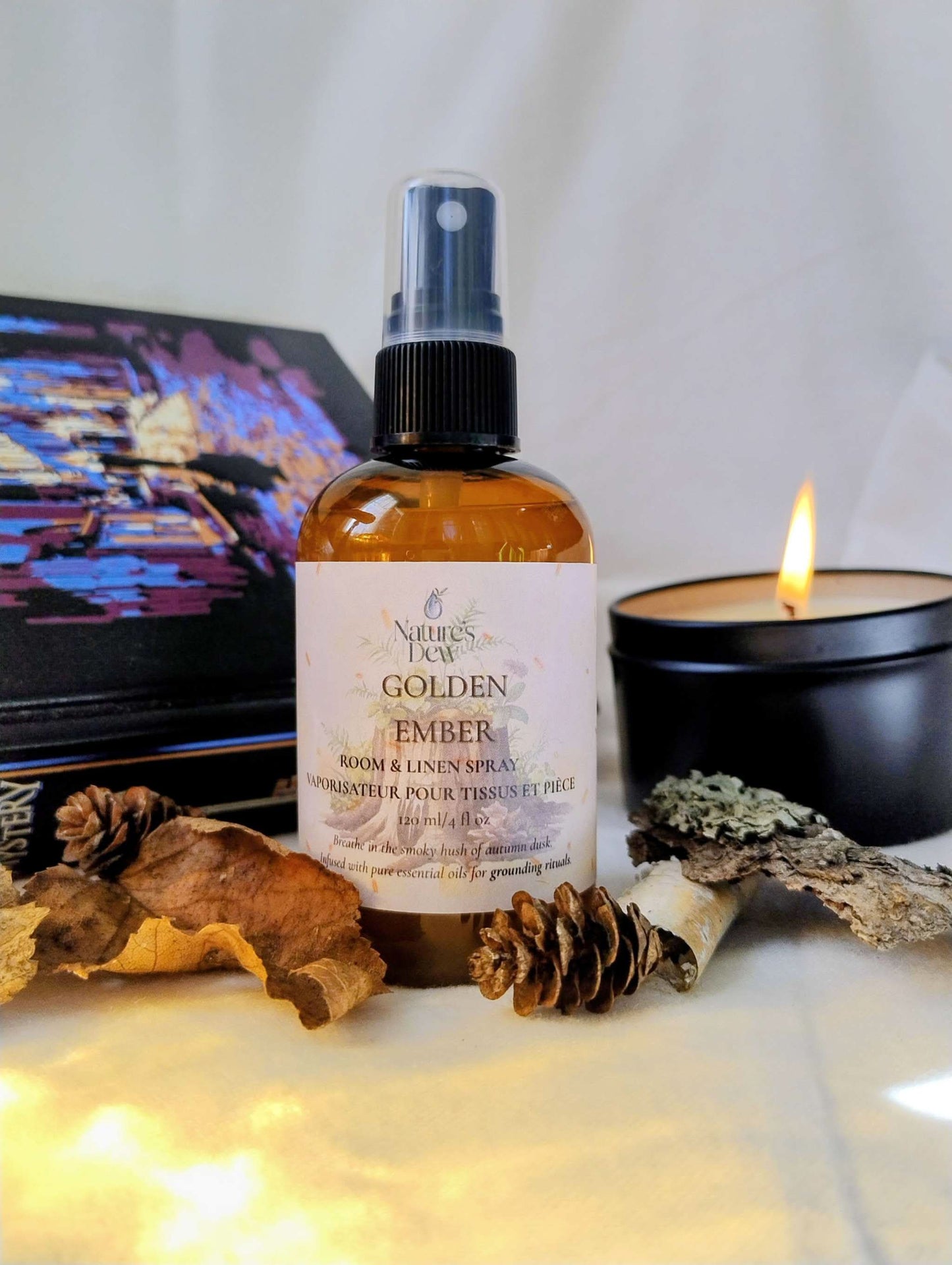 Golden Ember Linen & Room Spray bottle with natural elements and lit candle creating a warm, grounding atmosphere