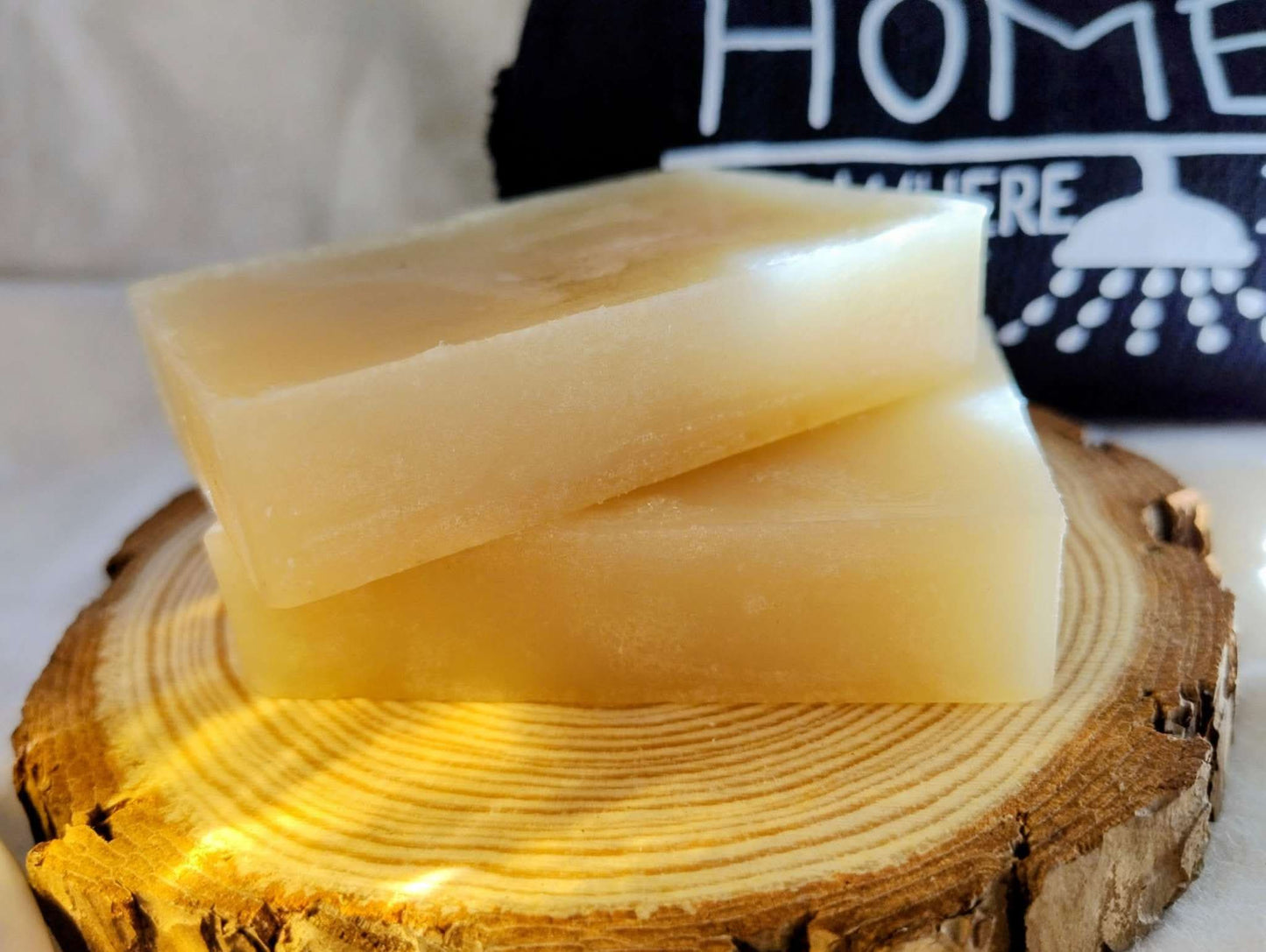Two golden-yellow bars of Golden Hearth Ritual Soap stacked on a wooden slab with a cozy home-themed background