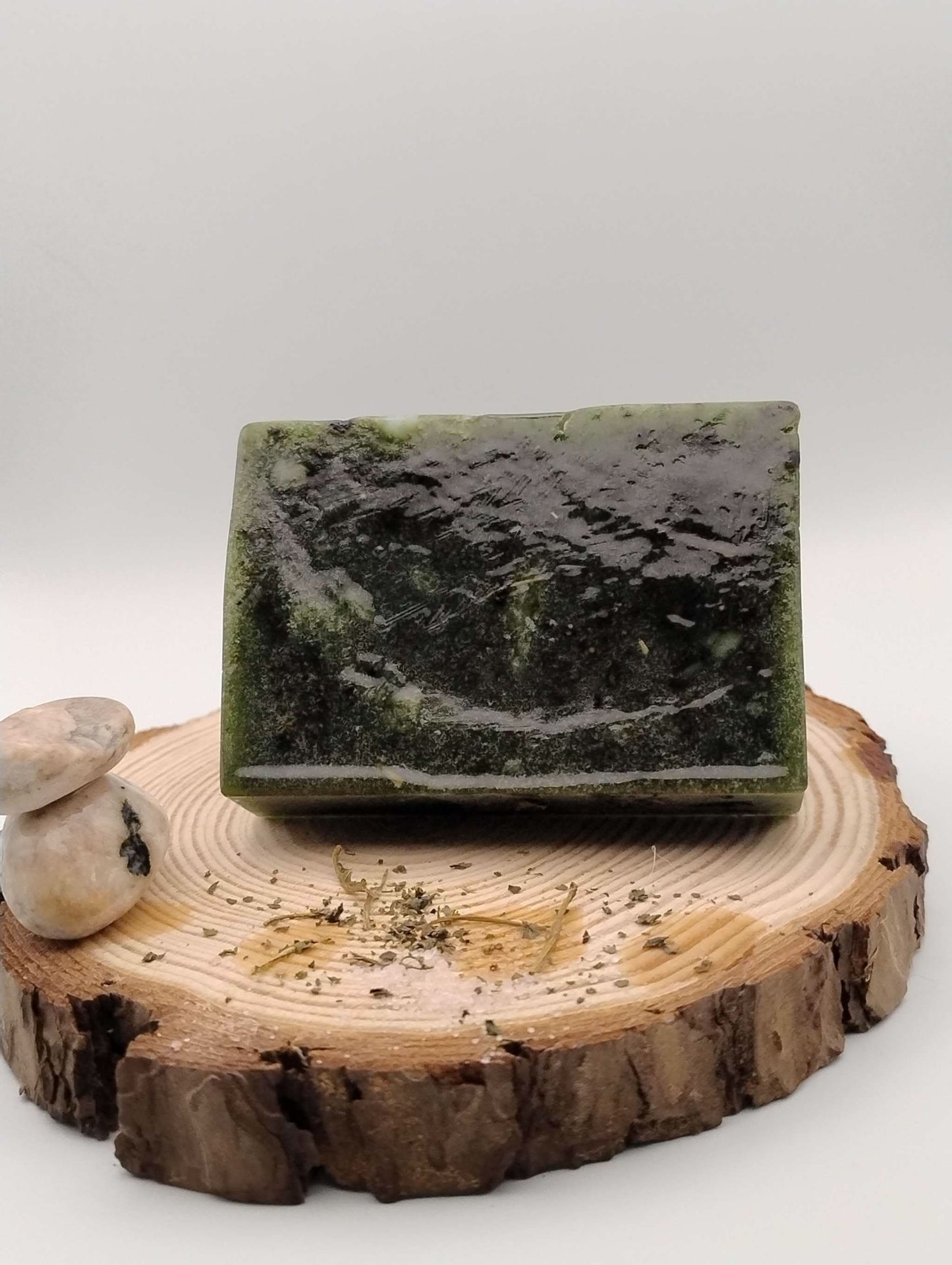 Green Forest Rain Ritual Soap bar on a wooden slab with natural stones and herbs, evoking a fresh pine and rain-soaked forest atmosphere