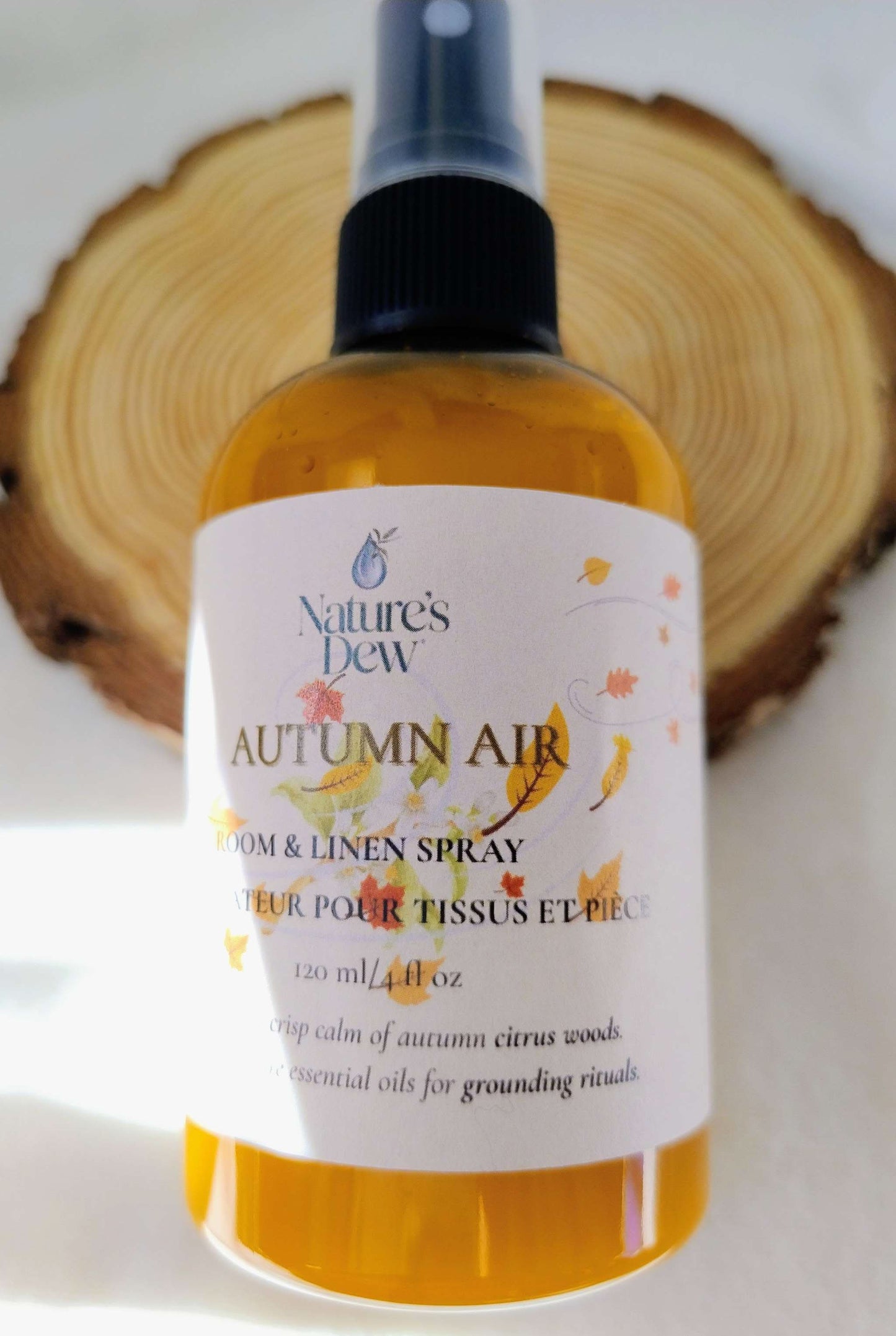 Autumn Air Room & Linen Spray with crisp citrus and warm cedarwood scent in amber spray bottle on wooden background