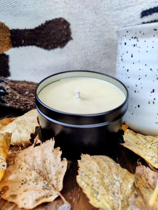 Woodland Spice Candle in black tin surrounded by autumn leaves and cozy home decor, evoking warm spiced woods and forest hearth ambiance