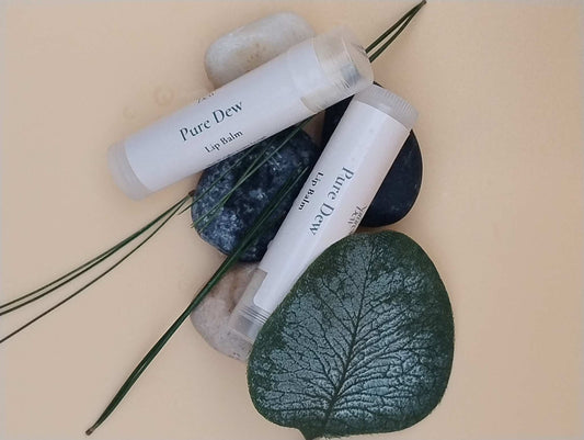 Pure Dew Lip Balm tubes on natural stones and leaves background.