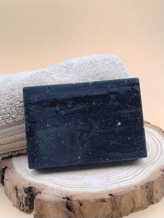 Evergreen Citrus Ritual Soap Bar with a creamy lather and earthy-citrus aroma, displayed on a wooden slab with a towel background.