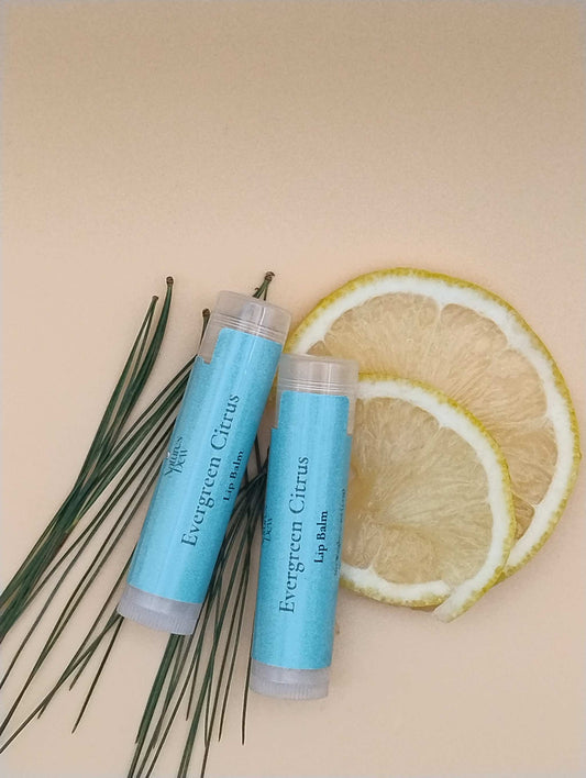 Evergreen Citrus Lip Balm with citrus slices and pine needles background.